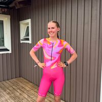 Triatleta donna con trisuit personalizzata rosa con motivo unico in piedi all'aperto