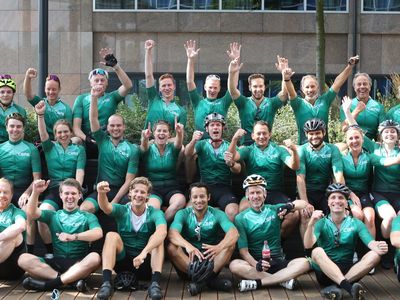 Grande squadra ciclistica con maglie da ciclismo personalizzate verdi che festeggia insieme dopo un'uscita