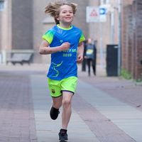 Child wearing custom running shirt and shorts running during event in urban setting