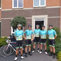 Equipo de ciclismo con maillots personalizados en azul y verde posando al aire libre con bicicletas de carretera