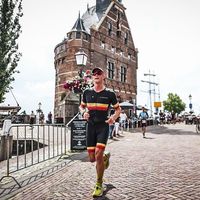 Triatleta con trisuit personalizzata che corre durante una gara in una citta con edifici storici