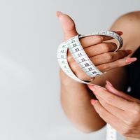 Vrouwen hand met meetlint maattabel