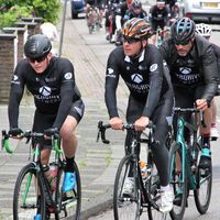 Ciclistas con maillots personalizados en negro montando bicicletas de carretera durante una salida en grupo en la ciudad