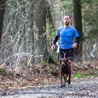 Runner wearing custom running shirt training with dog on forest trail outdoors