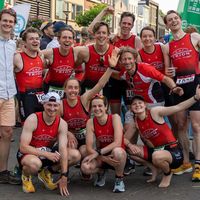 Team di triathlon Trion con trisuit personalizzate rosse che festeggia insieme durante una gara