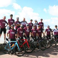 Team ciclistico RPS con maglie personalizzate viola in posa con bici da corsa all'aperto