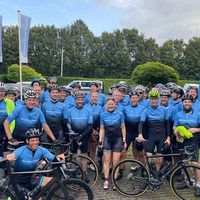 Grande team ciclistico con maglie personalizzate blu e nere in posa con bici all'aperto