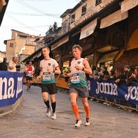 Runners wearing custom running shirts competing during city race event with spectators