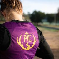 PTC custom running shirt in purple with logo on back worn by athlete outdoors