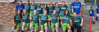 Squadra di calcio con kit personalizzati verdi in posa insieme prima della partita all'aperto