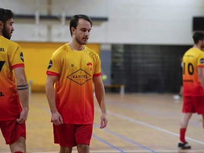 Giocatori di futsal con maglie da calcio personalizzate in sfumatura gialla e rossa durante una partita indoor