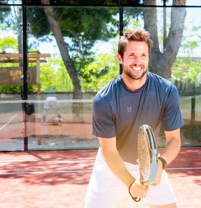 jeune homme jouant au padel en extérieur sur un court d’été avec un maillot personnalisé